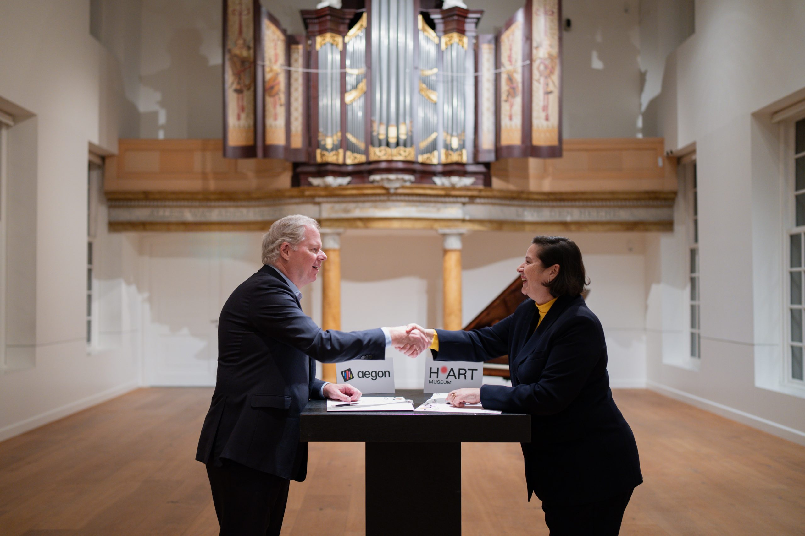 Lard Friese, CEO van Aegon en Annabelle Birnie, directeur van H'ART Museum tekenen de overeenkomst in de Kerkzaal van H'ART Museum.